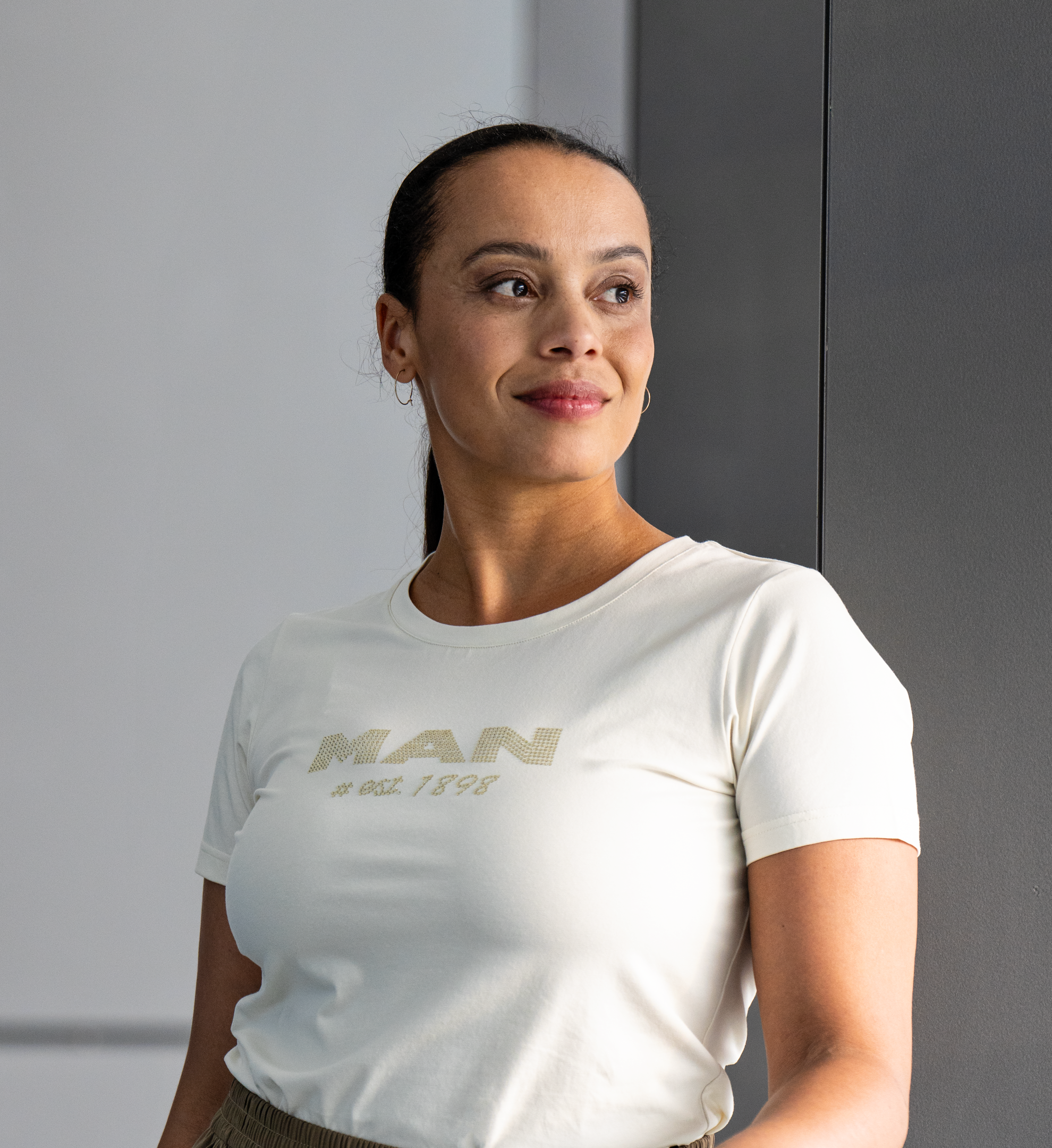 Frau in einem cremeweißen MAN-T-Shirt mit dezentem Logo, elegant und stilvoll aus der MAN Ladies Collection.