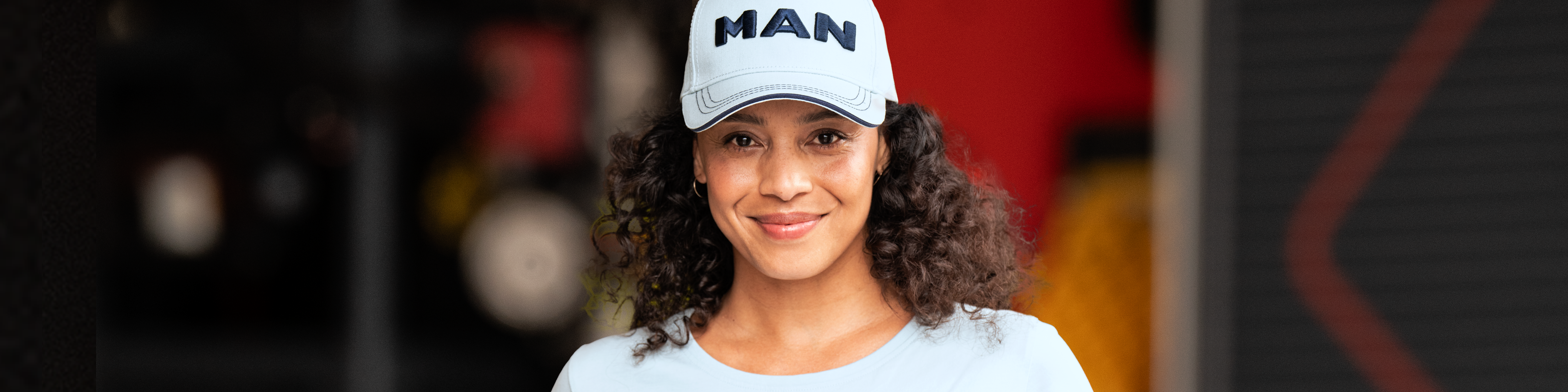 Ein Model trägt eine MAN Cap und T-Shirt aus der Damenkollektion. Entdecken Sie stilvolle Damenbekleidung und Accessoires im offiziellen MAN Fan Shop.