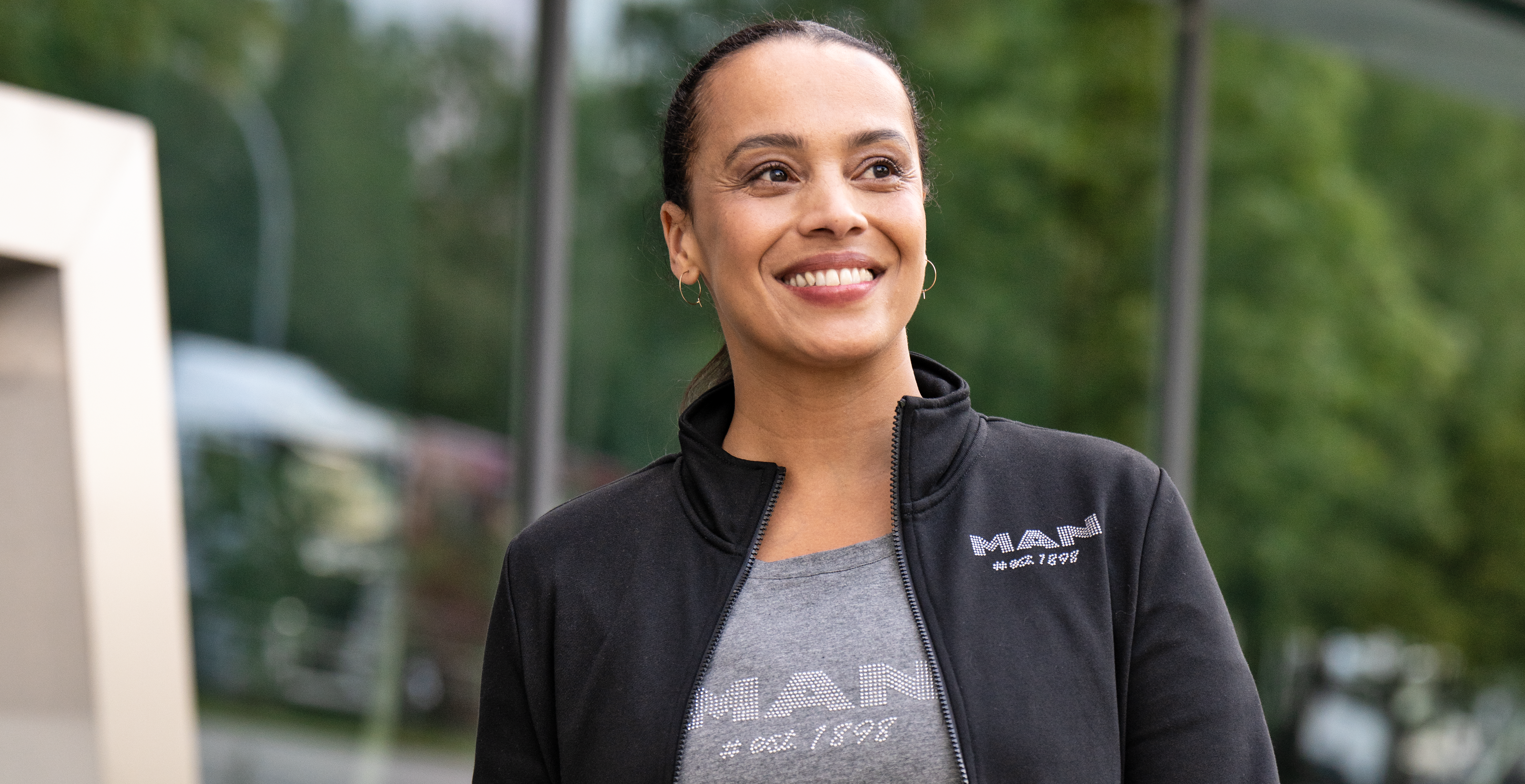 Lächelnde Frau in MAN-Jacke und T-Shirt aus der Ladies Collection, ideal für stilbewusste Frauen, die Komfort und Eleganz suchen.